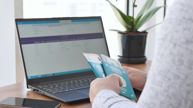 A man sits at a table and plans a vacation with his family through the website booking.com, a man holds Kazakhstan passports and books a hotel through a computer. High quality 4k footage