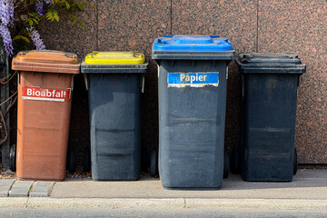 labeled old recycling bins for paper, bio waste, and more, placed on a German street