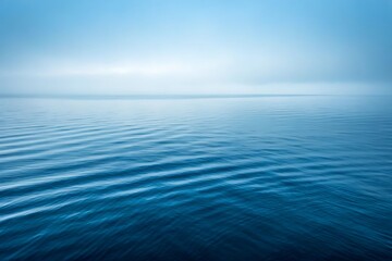 Obraz premium Serene Horizon: A tranquil expanse of deep blue water stretches towards the misty horizon, creating a calming and peaceful scene, perfect for evoking a sense of calm and introspection.