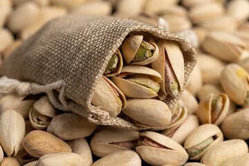shelled pistachio nuts with added salt in a wooden bowl and a linen bag