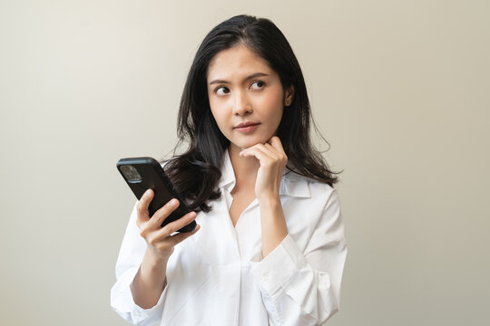 Anxiety Asian woman holding a smartphone and thinking about fake news in app.