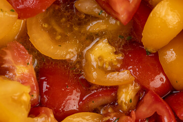 red and yellow tomatoes during salad preparation, preparation of salad from sliced tomatoes with spices and oil