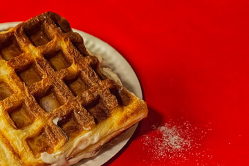 Belgian waffles on a white plate against a red background close-up.