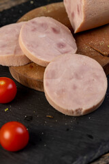 chicken ham from different pieces of meat during slicing and ripe red tomatoes