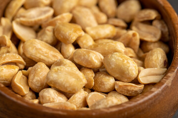 peanuts in a bowl, crunchy peanuts without shells on a black slate board, side view
