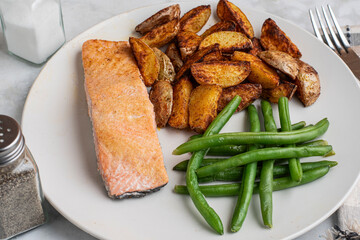 baked seasoned salmon  with green beans and potato wedges