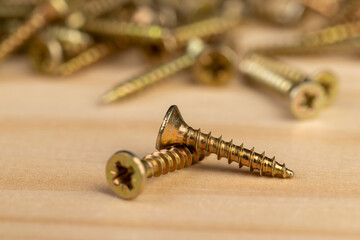 screws for construction work lying on a pine board, metal self tapping screws for connecting wooden or metal elements, side view