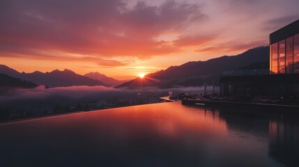 Fototapeta premium Infinity pool overlooking misty alpine valley at sunrise in Kitzbühel, Austria. Elegant mountain resort with glowing orange and pink sky, tranquil scenery, soft light, and luxurious atmosphere.