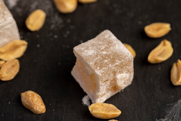 Turkish delight cubes and toasted peanuts on a slate surface, top view
