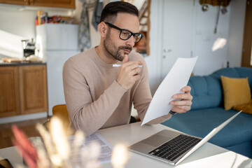 Focused entrepreneur reading documents and working from home office