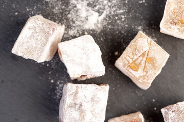 cubes of Turkish delight with the addition of red berries in powdered sugar close up, view from above