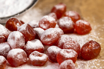 sweet dehydrated candied fruits of kumquat in white powdered, dried fruits are on paper closeup, side view