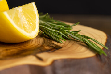 yellow lemon on a black slate board, freshly sliced lemon on a black board with green rosemary