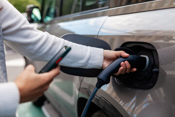 Charging an electric car in an urban setting. A modern woman engages with sustainable technology and green energy solutions for everyday mobility