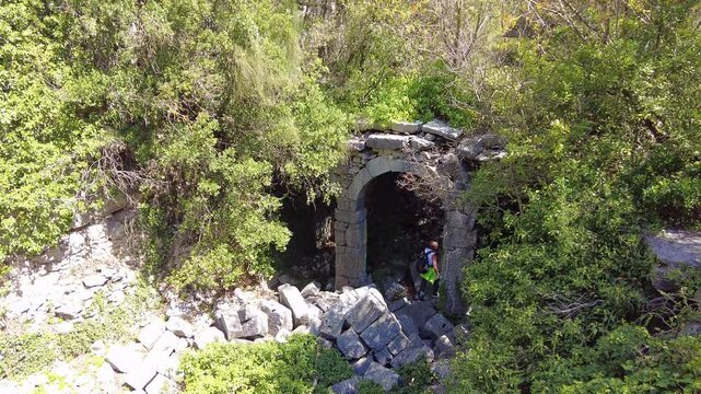 4K A traveler explores the ancient, overgrown stone arches deep within the ruins of Termessos, a lost Pisidian city high in the Taurus Mountains (Gulluk Mountain) near Antalya, Turkey