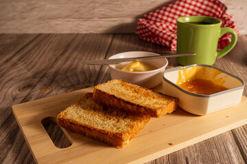 Toasted sliced bread with butter and apricot jam for breakfast on wooden table