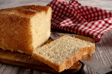 Loaf of freshly baked bread with a slice cut off on wooden board