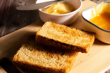 Toasted sliced bread with butter and marmalade on wooden cutting board