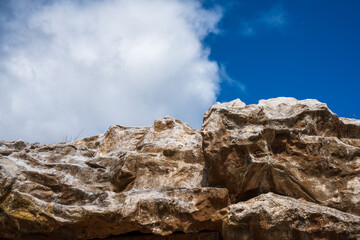 Background of mountainous cliff, rocky edge, blue sky and white cloud. Perfect for creative idea of outdoor activities, summer sports or sporty vibe. An inspiration, encouragement to join the nature