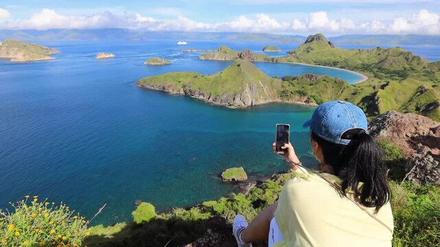 Young woman on the top of Padar island viewpoint taking pictures on the beautiful scenery Komod Labuan Bajo Indonesia
