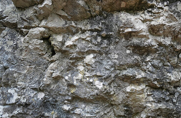 Natural close-up of a weathered rock surface with rough texture, cracks, and mineral layers — perfect for backgrounds or geology themes