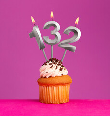 Birthday candle number 132 with cupcake on violet background