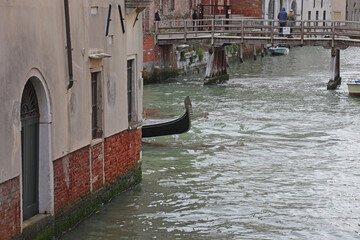Bow of Gondola boat behind the corner of and houses on the navigagle waterway in Venice Island in...