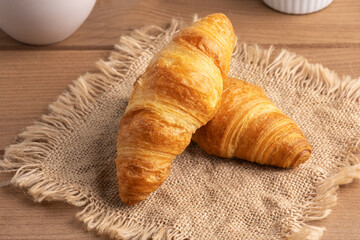 Freshly baked croissants resting on a textured cloth display at a bakery during the morning hours