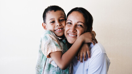 Happy Latin American mother and son hugging each other at home, Family love concept