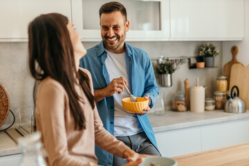 Happy couple enjoying breakfast and sharing a laugh in modern kitchen