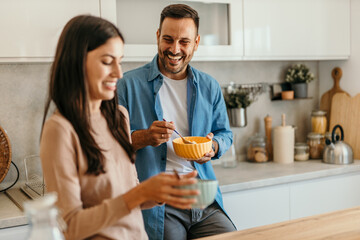 Happy couple enjoying breakfast in modern kitchen