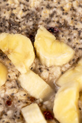 banana in porridge close up, boiled oatmeal porridge with chia seeds, berries and fresh banana
