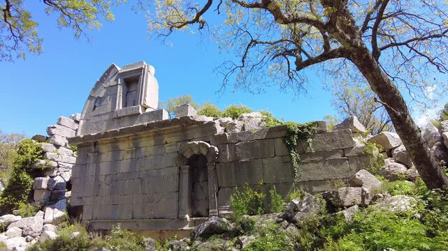 4K The crumbling stone walls of Roman bath ruins in Termessos, Pisidian city hidden in the Taurus Mountains (Gulluk Mountain) near Antalya, Turkey. Ancient architecture surrounded by green vegetation