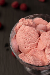 raspberry ice cream in a glass, sweet frozen red ice cream with raspberry flavor closeup, The berries are scattered on the table, side view