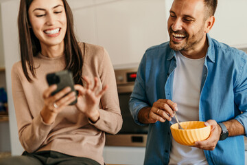 Couple enjoying breakfast and social media in modern kitchen