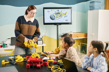 Educator demonstrating engineering concepts to children in a vibrant classroom. Students engaging with tools and models, fostering hands-on learning and creativity