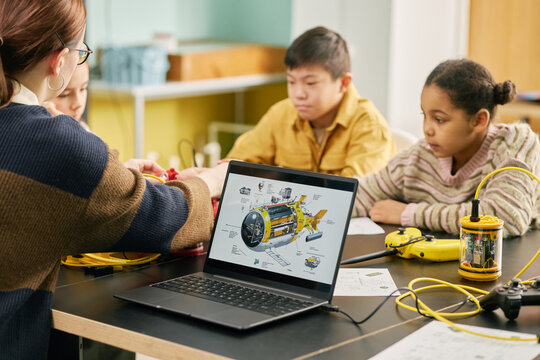 Students participating in interactive science lesson with a teacher guiding them. Educational tools and technology are used to enhance learning experience