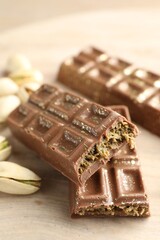 Delicious Dubai chocolate bars and pistachios on wooden table, closeup