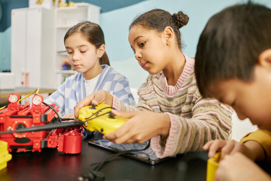 Children exploring robotics through hands-on activity in classroom setting with focus and collaboration evident in their expressions. Multiracial group actively participating in learning experience