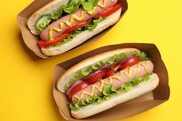 Tasty hot dogs on yellow background, flat lay