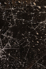 water covered broken glass with a lot of damage on a dark background, wet thin broken glass