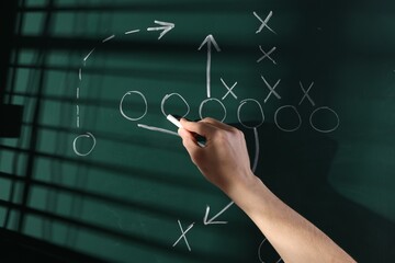 Man drawing American football game scheme on chalkboard, closeup