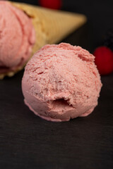 melting ice cream on a slate board, sweet cold pink ice cream with strawberry flavor, ice cream in a waffle cone