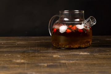 rosehip on a black tea table, a harvest of fresh red fruits from a rose that are used in the preparation of tea in a teapot