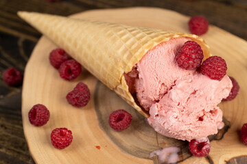pink raspberry-flavored ice cream lies on a walnut board, ripe red raspberries and raspberry cold natural ice cream on the table, close up