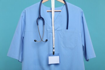 Medical worker uniform with stethoscope and badge on hanger against blue background
