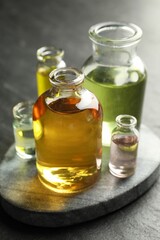 Open perfume bottles with aromatic essential oils on dark textured table, closeup
