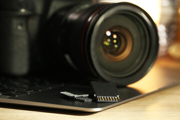 SD memory cards, laptop and photo camera on wooden table, closeup