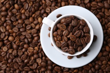 Cup and saucer on coffee beans, top view. Space for text