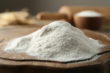 Pile of wheat flour on wooden board, closeup